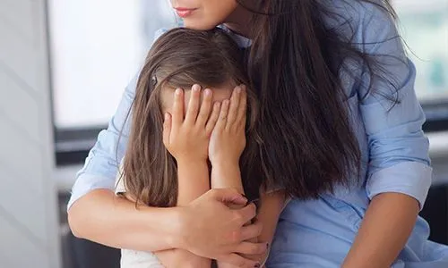 Enfant qui pleure dans les bras de sa maman